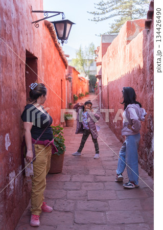 Three women standing in a narrow alleyway Three women standing in a narrow alleyway 134426490