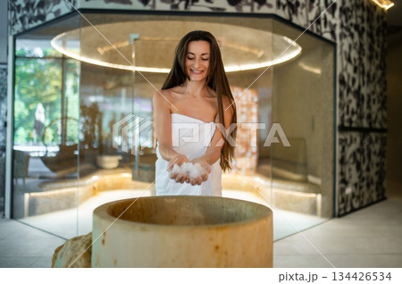Excited young woman in a towel preparing for the spa salt therapy in spa center Excited young woman in a towel preparing for the spa salt therapy in spa center 134426534
