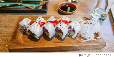 Colorful sushi rolls arranged on wooden plate with dipping sauce and garnish 134426571