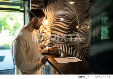 Tall dak-haired man standing at the reception desk in the hotel 134426621
