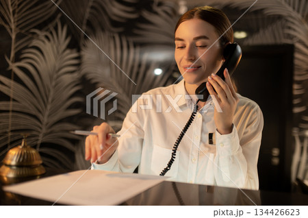 Receptionist talking on the phone while arranging accommodation for the customer 134426623