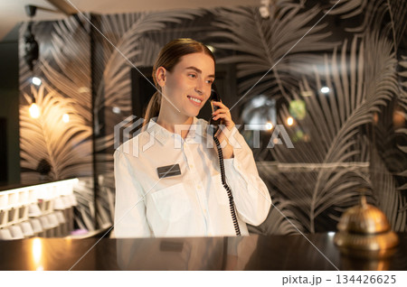 Receptionist talking on the phone while arranging accommodation for the customer 134426625