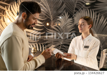 Receptionist talking to a male customer and arranging accommodation for him 134426627
