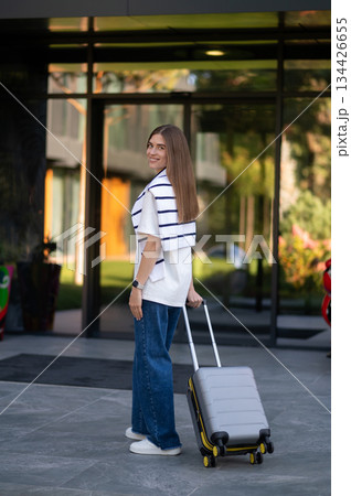 Long-haired cute young woman with a suitcase near the hotel 134426655