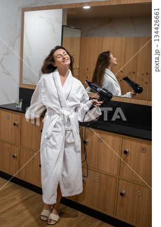 Long-haired caucasian young woman in white robe drying her hair 134426661