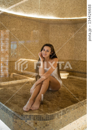 Pretty young woman in white towel on a massage table in a spa center Pretty young woman in white towel on a massage table in a spa center 134426688