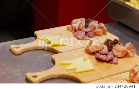 Assorted cured meats and cheese on wooden cutting boards in kitchen 134426941