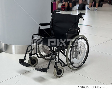 Close-up of empty wheelchair standing in airport terminal hall. Inclusive transportation concept, mobility assistance availability, accessibility awareness, and support for passengers. 134426992