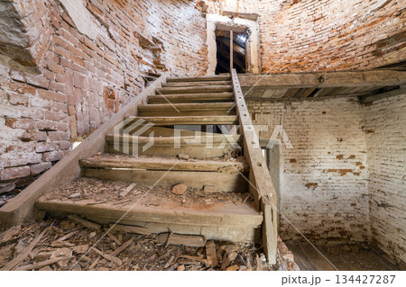 Large spacious forsaken empty basement room of ancient building or palace with cracked plastered brick walls, dirty floor and wooden staircase ladder. Large spacious forsaken empty basement room of ancient building or palace with cracked plastered brick walls, dirty floor and wooden staircase ladder. 134427287