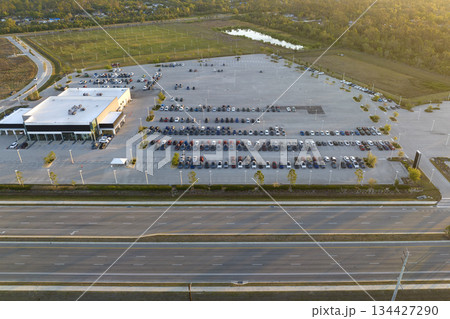 Large parking lot of local dealer with many brand new cars parked for sale on highway roadside. Development of american automotive industry and distribution of manufactured vehicles concept Large parking lot of local dealer with many brand new cars parked for sale on highway roadside. Development of american automotive industry and distribution of manufactured vehicles concept 134427290