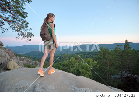 Hiker woman walking on mountain footpath enjoying evening nature. Lonely female traveler traversing wilderness trail. Healthy lifestyle concept Hiker woman walking on mountain footpath enjoying evening nature. Lonely female traveler traversing wilderness trail. Healthy lifestyle concept 134427323