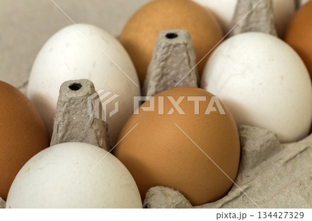 Hen eggs in open cardboard egg carton on kitchen table light copy space background. Healthy organic food and diet concept. Hen eggs in open cardboard egg carton on kitchen table light copy space background. Healthy organic food and diet concept. 134427329