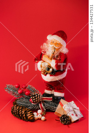 Santa Claus with Christmas Gifts and Pine Cones on Red Background Santa Claus with Christmas Gifts and Pine Cones on Red Background 134427531