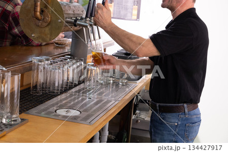 Berlin, Germany - January 22, 2024: Bartender pouring beer into glass at bar counter 134427917