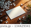 Shiny gems scattered on wooden surface with blank card nearby in warm light 134429341