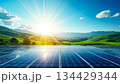 Solar panels capture sunlight on a hilltop beneath a vibrant sky and mountains during a beautiful dawn 134429344