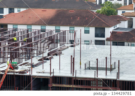 Construction site with hardhat workers assembling metal frame walls. Aerial view of large development area of commercial structure. Real estate market in the USA Construction site with hardhat workers assembling metal frame walls. Aerial view of large development area of commercial structure. Real estate market in the USA 134429781