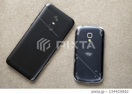 Comparison of two black mobile phones, old cellphone and new modern on light cloth copy space background. Technology progress and replacement concept. 134429802