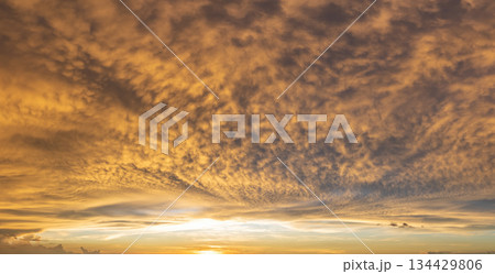 Colorful sunset sky with setting sun behind vivid orange and yellow clouds 134429806