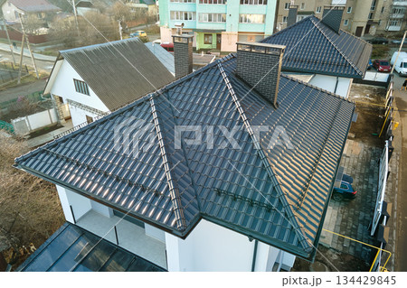Closeup of house roof top covered with ceramic shingles. Tiled covering of building 134429845