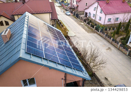 Close-up surface of lit by sun blue shiny solar photo voltaic panels system on building roof. Renewable ecological green energy production concept. Close-up surface of lit by sun blue shiny solar photo voltaic panels system on building roof. Renewable ecological green energy production concept. 134429853
