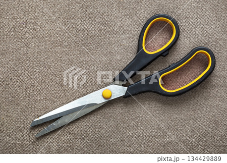 Close-up of sharp steel metal scissors isolated on light cloth copy space background. Household equipment, office or school tools. 134429889