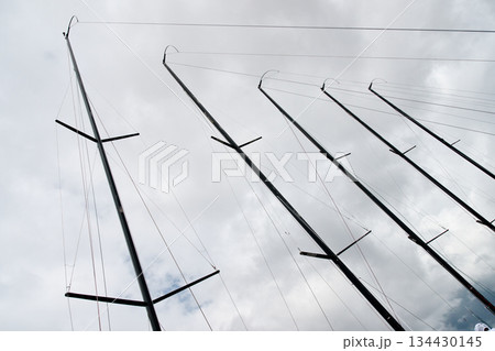 Few masts of sailboats moored in yacht club, ropes and aluminum, cloudy weather 134430145