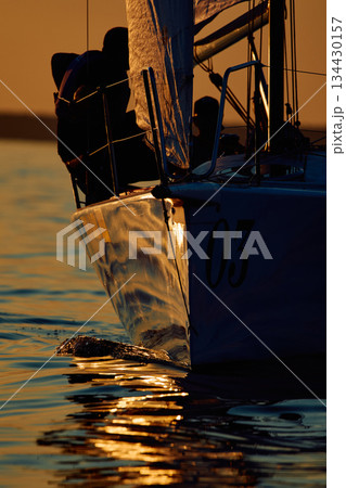 Sailing regatta in the Gulf of Finland at sunset, few sailing yachts competing in a race, splashing water from under the boats, teamwork, board the boat Sailing regatta in the Gulf of Finland at sunset, few sailing yachts competing in a race, splashing water from under the boats, teamwork, board the boat 134430157
