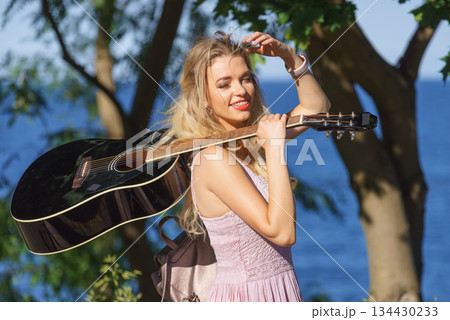 Woman playing acoustic guitar in park Woman playing acoustic guitar in park 134430233