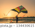 Colorful kite flying at sunset beach with silhouette of old city in background - Summer outdoor recreation activity 134430615
