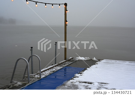 a wooden pier stretching into a calm, fog-covered lake 134430721