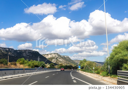 Sunny Sicilian road with mountains and trees 134430905