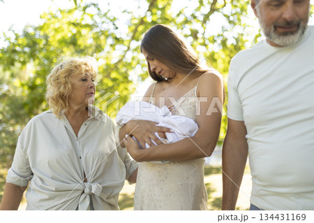 Mother breastfeeding baby with grandmother watching in park 134431169
