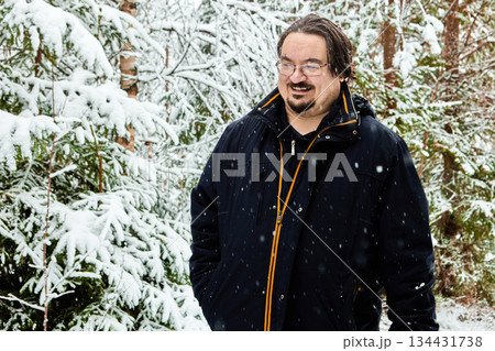 Mature man in warm clothing walks in snow covered forest. 134431738