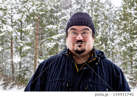 Startled anxious mood winter time dark knitted hat and dark jacket on white middle aged man standing in snowy forest with trees softly blurred behind. Startled anxious mood winter time dark knitted hat and dark jacket on white middle aged man standing in snowy forest with trees softly blurred behind. 134431740