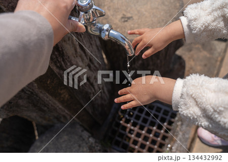 水道で手を洗う子供と蛇口をひねる親の手 134432992