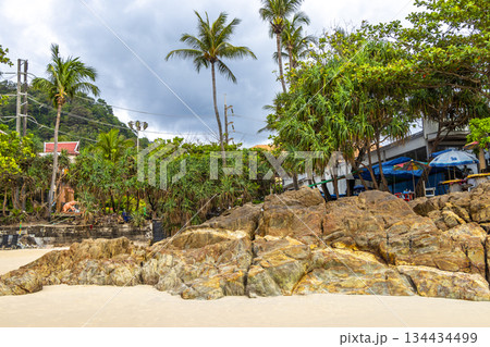 Rocky beach with rocks turquoise water palm trees Patong Thailand. 134434499