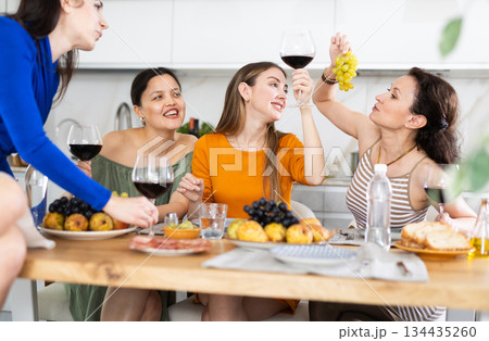 During gathering with friends, woman sit on table, enjoying food and wine, chatting, talking During gathering with friends, woman sit on table, enjoying food and wine, chatting, talking 134435260