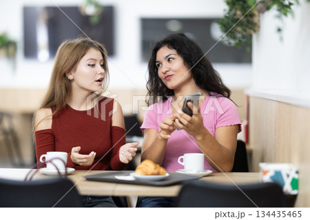 Two friends are chatting on smartphone in cafe Two friends are chatting on smartphone in cafe 134435465