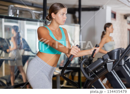 Sporty girl working out on elliptical machine in gym. Healthy active lifestyle concept 134435479