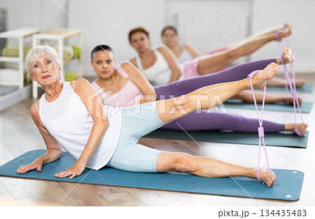 Senior lady doing xercises with figure eight resistance band in studio Senior lady doing xercises with figure eight resistance band in studio 134435483