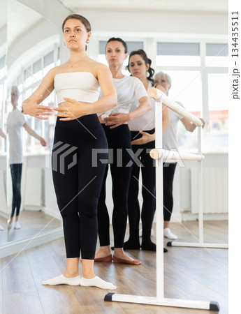 Group of women stand in position at ballet barre Group of women stand in position at ballet barre 134435511