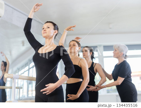 Fit woman maintaining fourth position during ballet workout Fit woman maintaining fourth position during ballet workout 134435516
