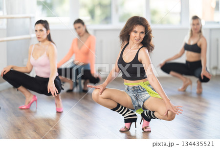 Female dancer performing sensual choreography in high heels at group rehearsal 134435521