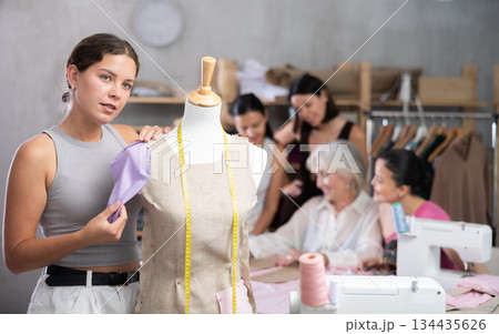 Young fashion design student shaping garment on mannequin Young fashion design student shaping garment on mannequin 134435626