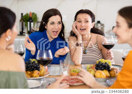 Girlfriends chatting and drinking wine in kitchen Girlfriends chatting and drinking wine in kitchen 134436280