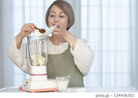 キッチンでヘルシージュースをジューサーで作るシニア女性 キッチンでヘルシージュースをジューサーで作るシニア女性 134436301