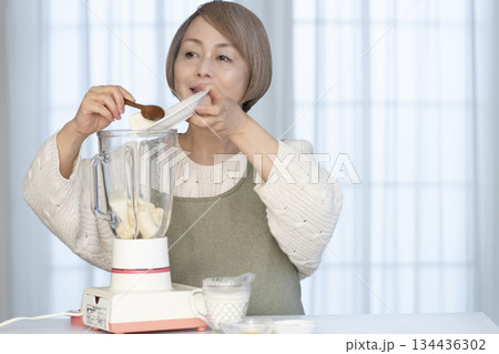 キッチンでヘルシージュースをジューサーで作るシニア女性 キッチンでヘルシージュースをジューサーで作るシニア女性 134436302