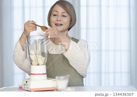 キッチンでヘルシージュースをジューサーで作るシニア女性 キッチンでヘルシージュースをジューサーで作るシニア女性 134436307