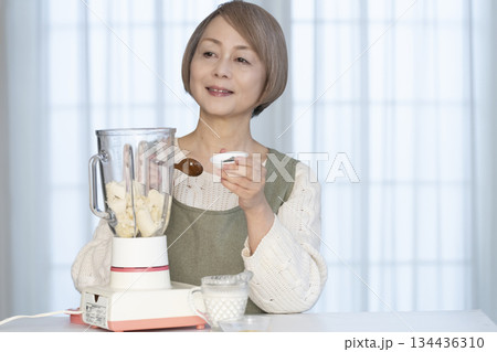 キッチンでヘルシージュースをジューサーで作るシニア女性 134436310